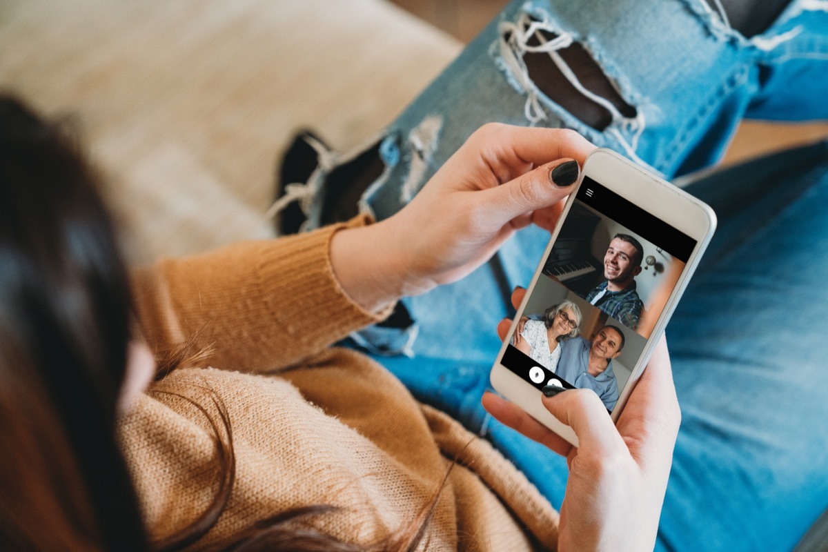 Young woman connecting with her family during quarantine. She's using a smartphone to call her family in Coronavirus COVID-19 time.