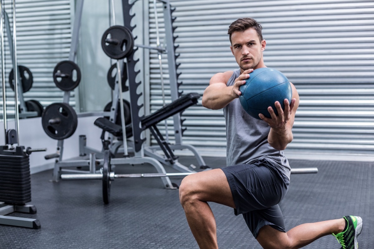 Young man at gym using weight ball