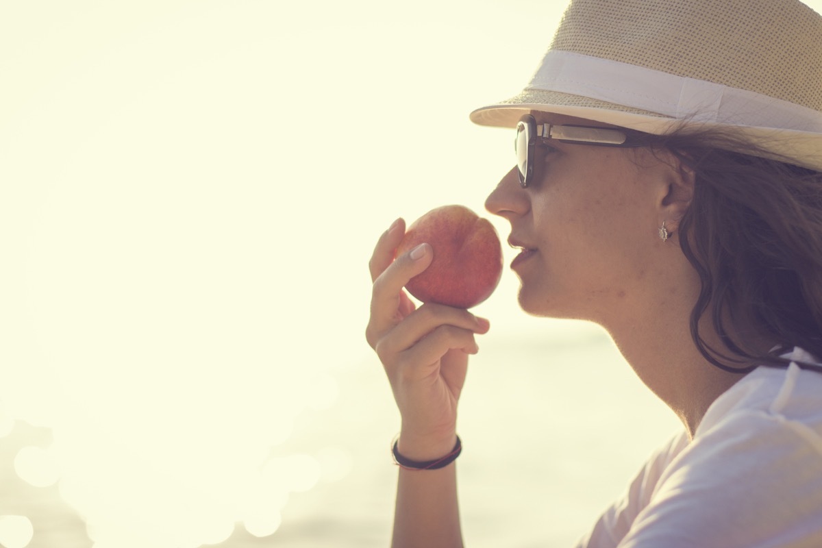 Young woman with the peach near the sea