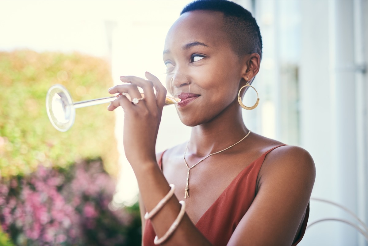 Cropped shot of a young woman drinking a glass of champagne outside