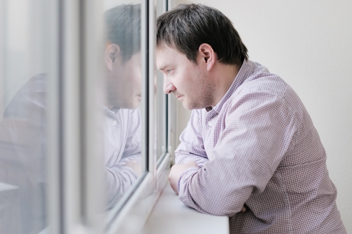 Man is sad and looking out the window in the winter